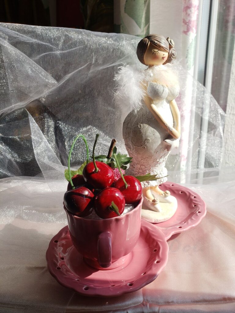 Pin-up en porcelaine tenant une soucoupe rose remplie de cerises, création de l’association Fleur et Chuchotement