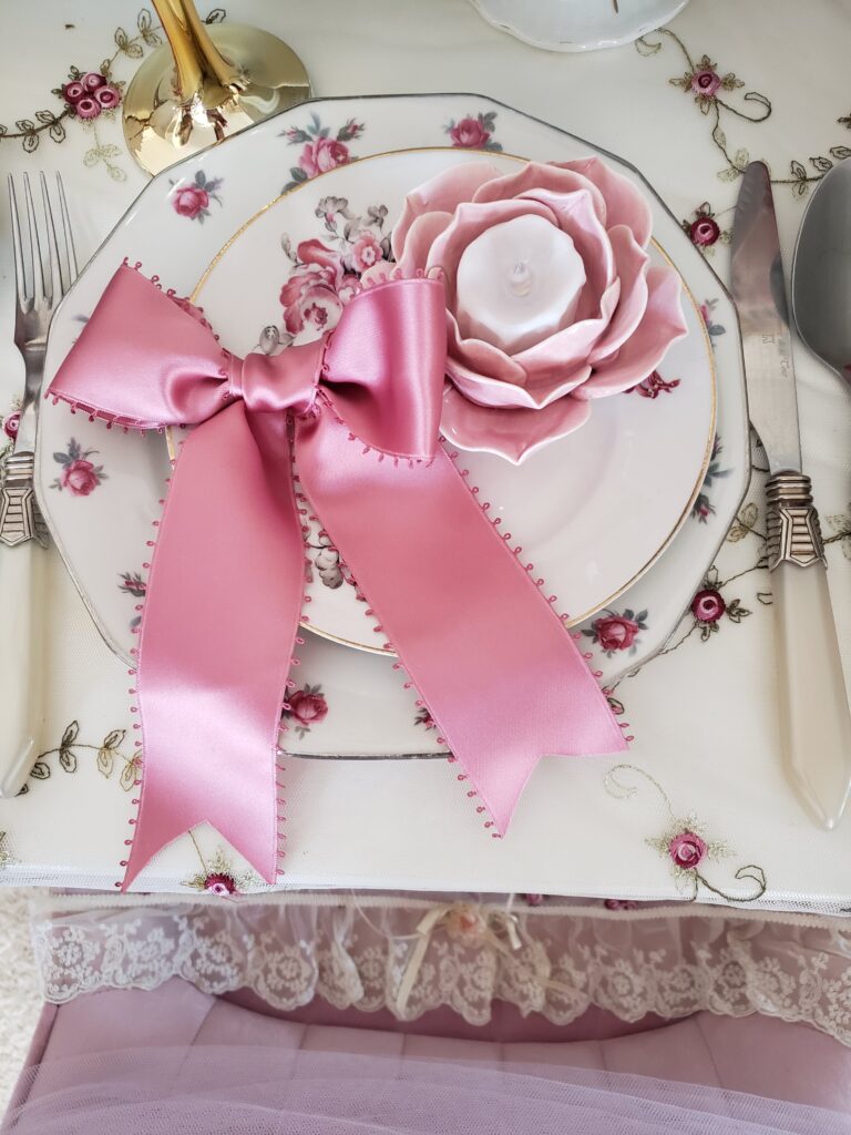 Assiette fleurie décorée d’un grand nœud rose en satin et d’une rose, pour une table pleine de douceur